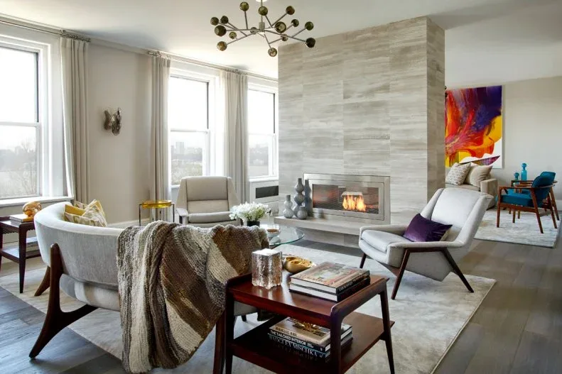 Pale horizontally layered fireplace wall with glazed opening, curved sofa and light lounge chair