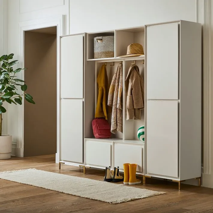 Pale freestanding entry storage with open coat hooks, upper cubbies, closed side cupboards and boots below
