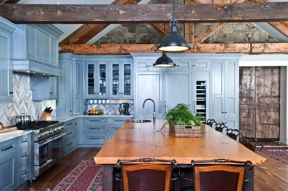 Light blue cabinets surround a wooden island beneath exposed timber beams