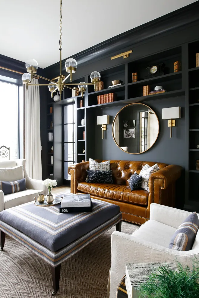 Dark built-in shelves and cabinetry frame a brown leather sofa
