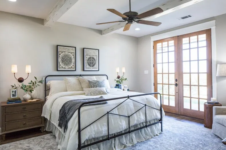 Neutral bedroom with wood-framed glazed doors, dark metal bed frame and wood bedside chests