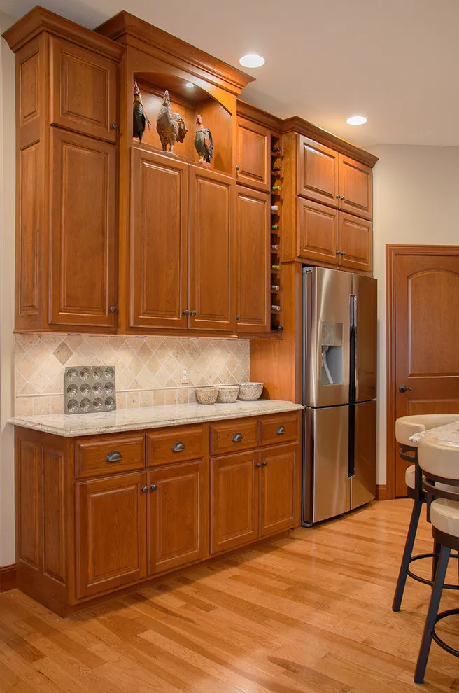 Tall wood kitchen storage and display openings surrounding a stainless refrigerator