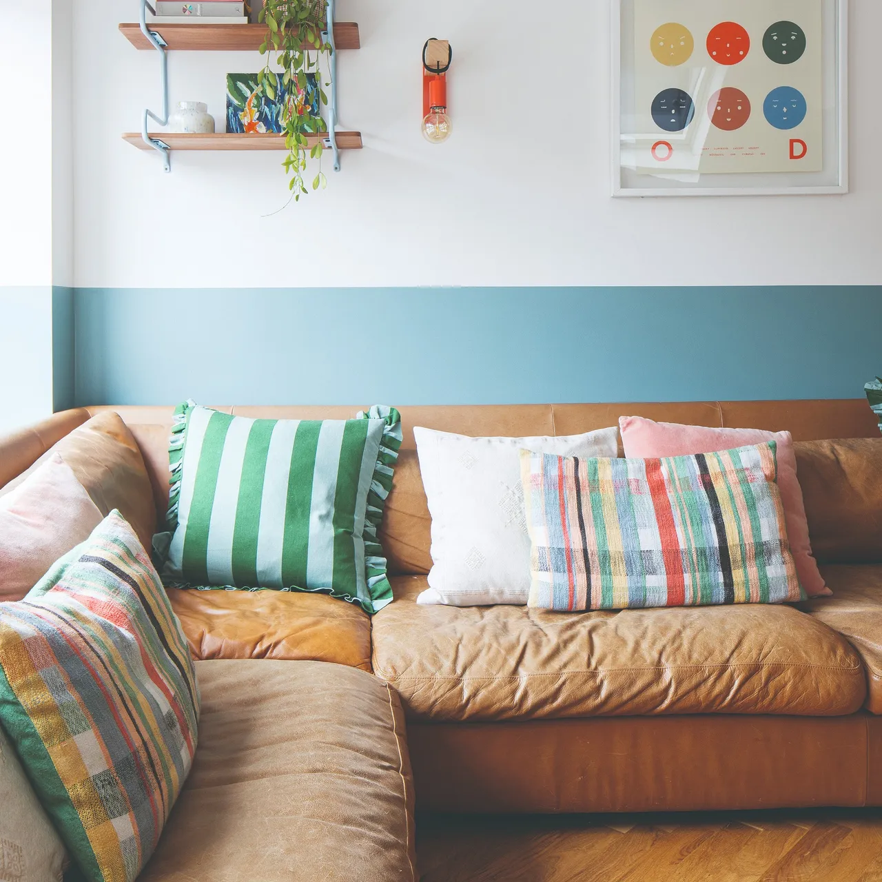 A wide blue painted band runs behind a tan sofa with striped cushions