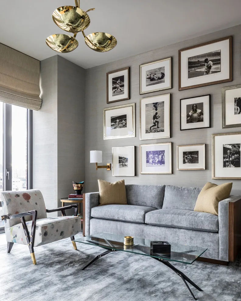 Black-and-white photographs form a structured group above a gray sofa