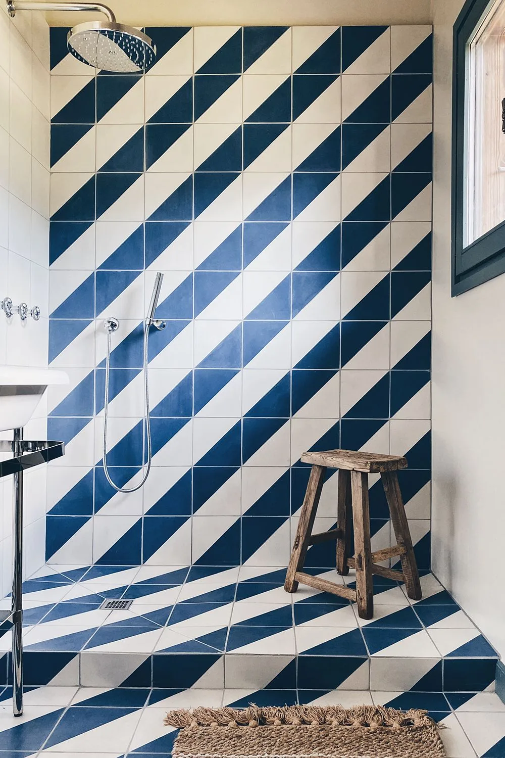 Diagonal navy and white tiles cover a shower wall and continue across the tiled floor