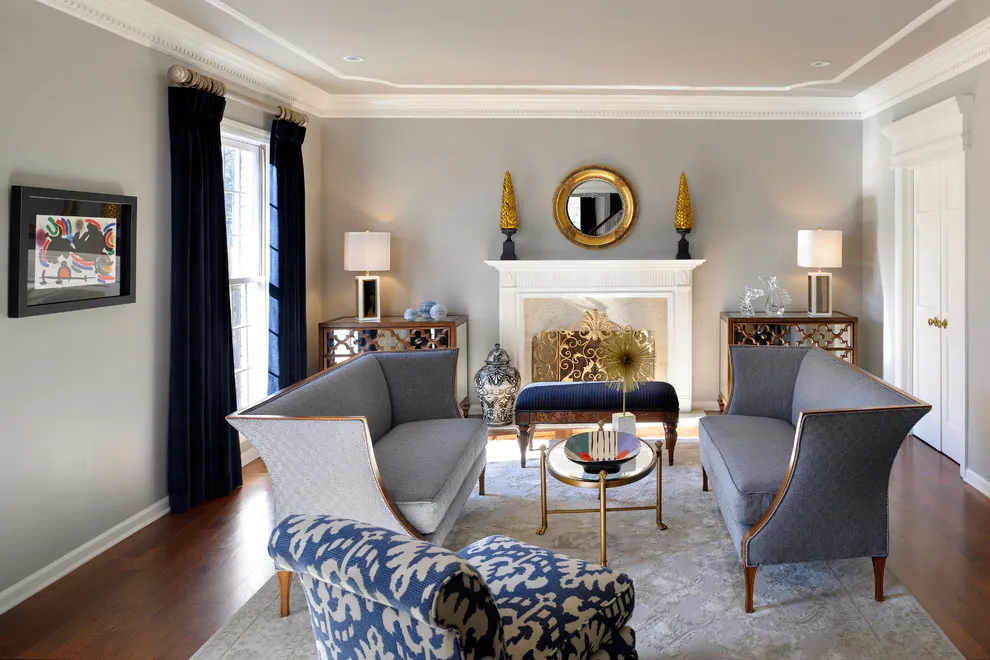 A curved blue-and-white patterned chair sits in front of gray sofas near a white fireplace