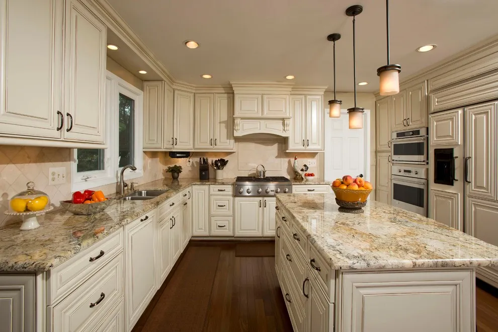 Cream paneled cabinets and an island surround speckled counters beneath small pendant lights