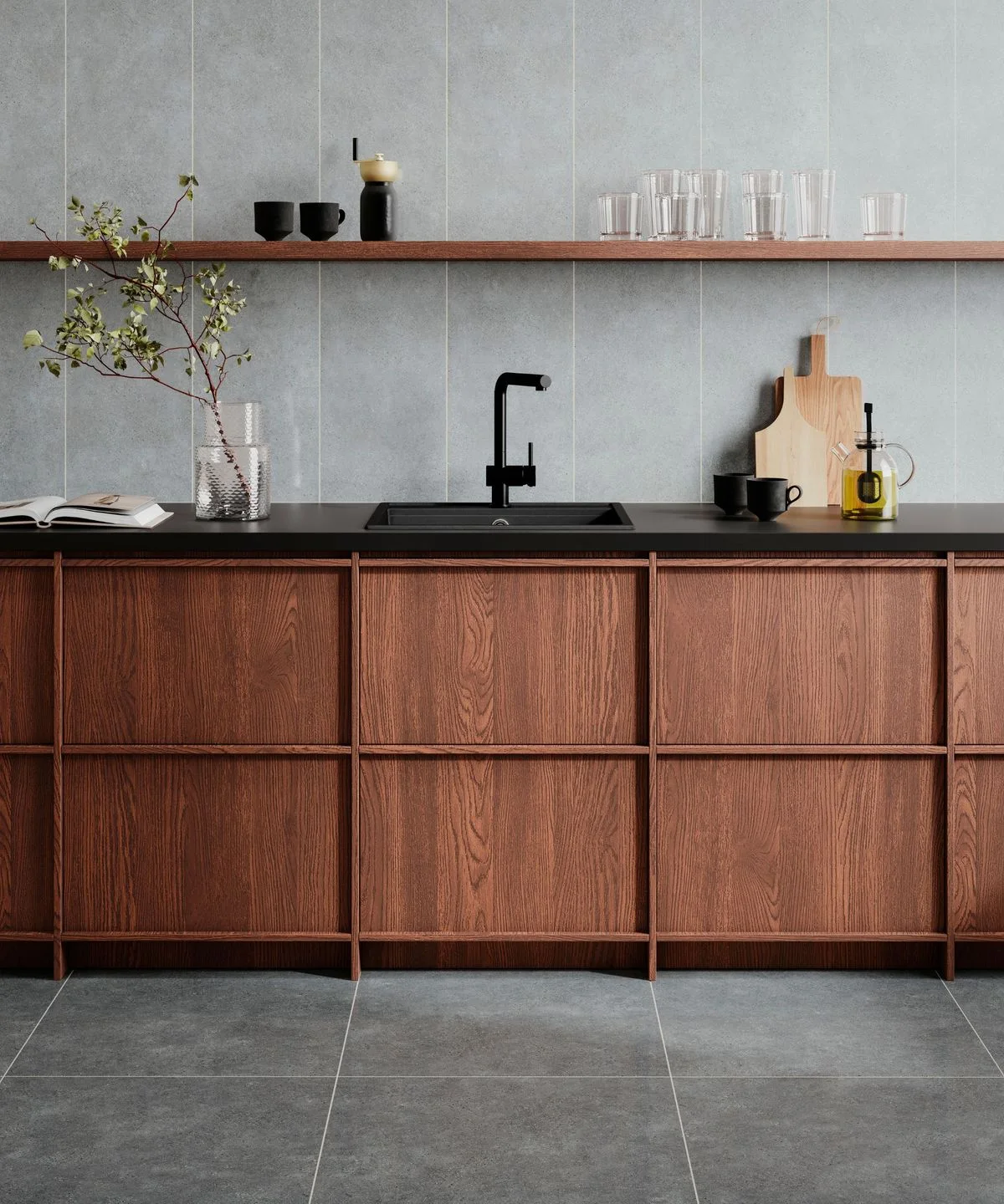 Wooden lower cabinets sit beneath a black counter and sink against large pale gray tiles with a narrow wooden shelf