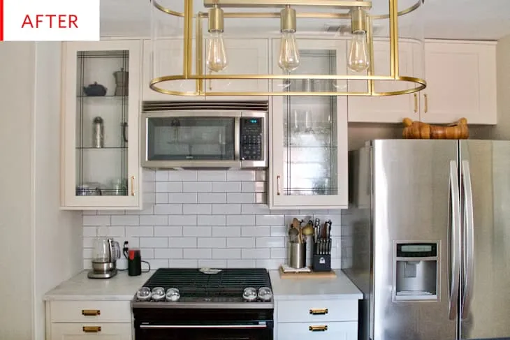 White farmhouse kitchen with subway tile behind the stove and brass pendant lighting