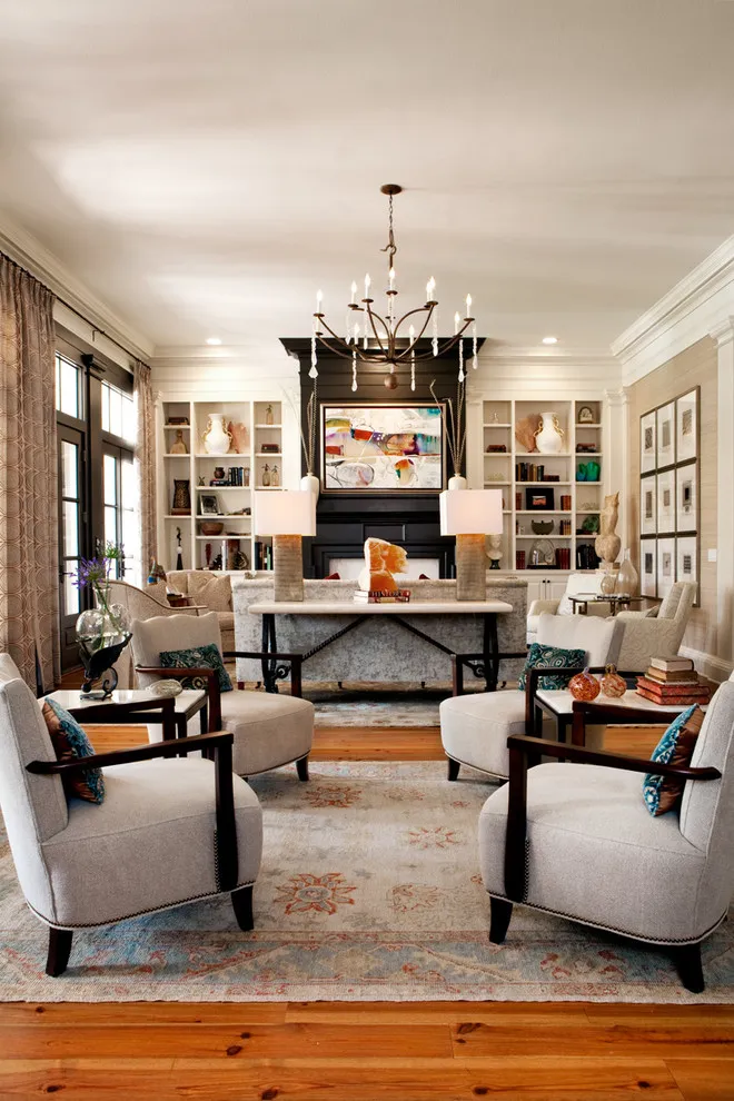 Four pale armchairs with dark timber arms sit along a long living room facing a fireplace