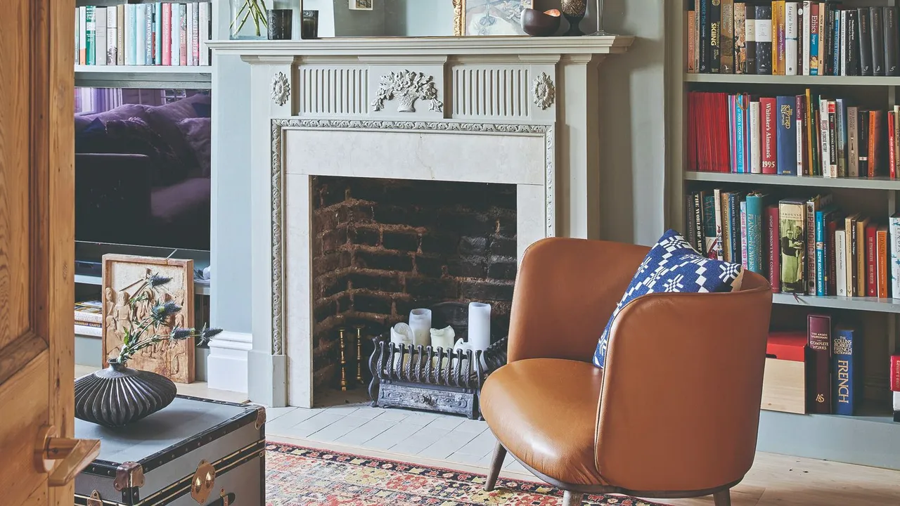 White ornate fireplace with dark brick opening holding pale pillar candles behind a low metal grate.