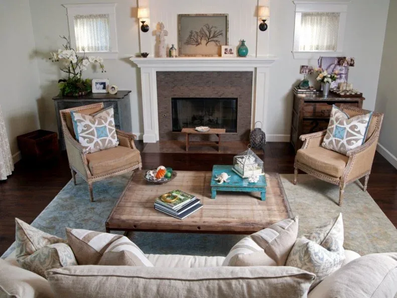 Pale sofa and two tan open-frame chairs around a large wooden table with a blue rug and turquoise tray.