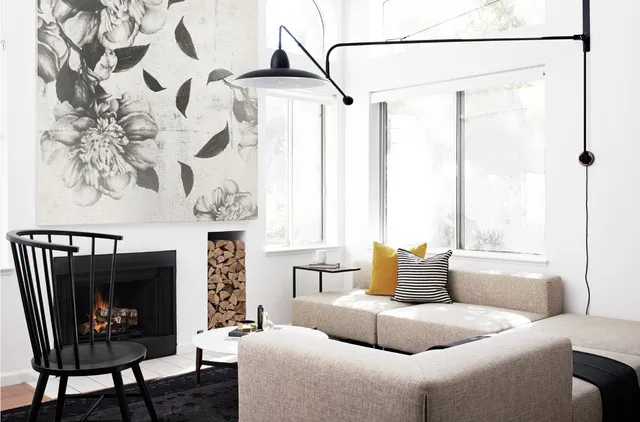 A large botanical wall pattern sits behind a pale corner sofa and dark chair.