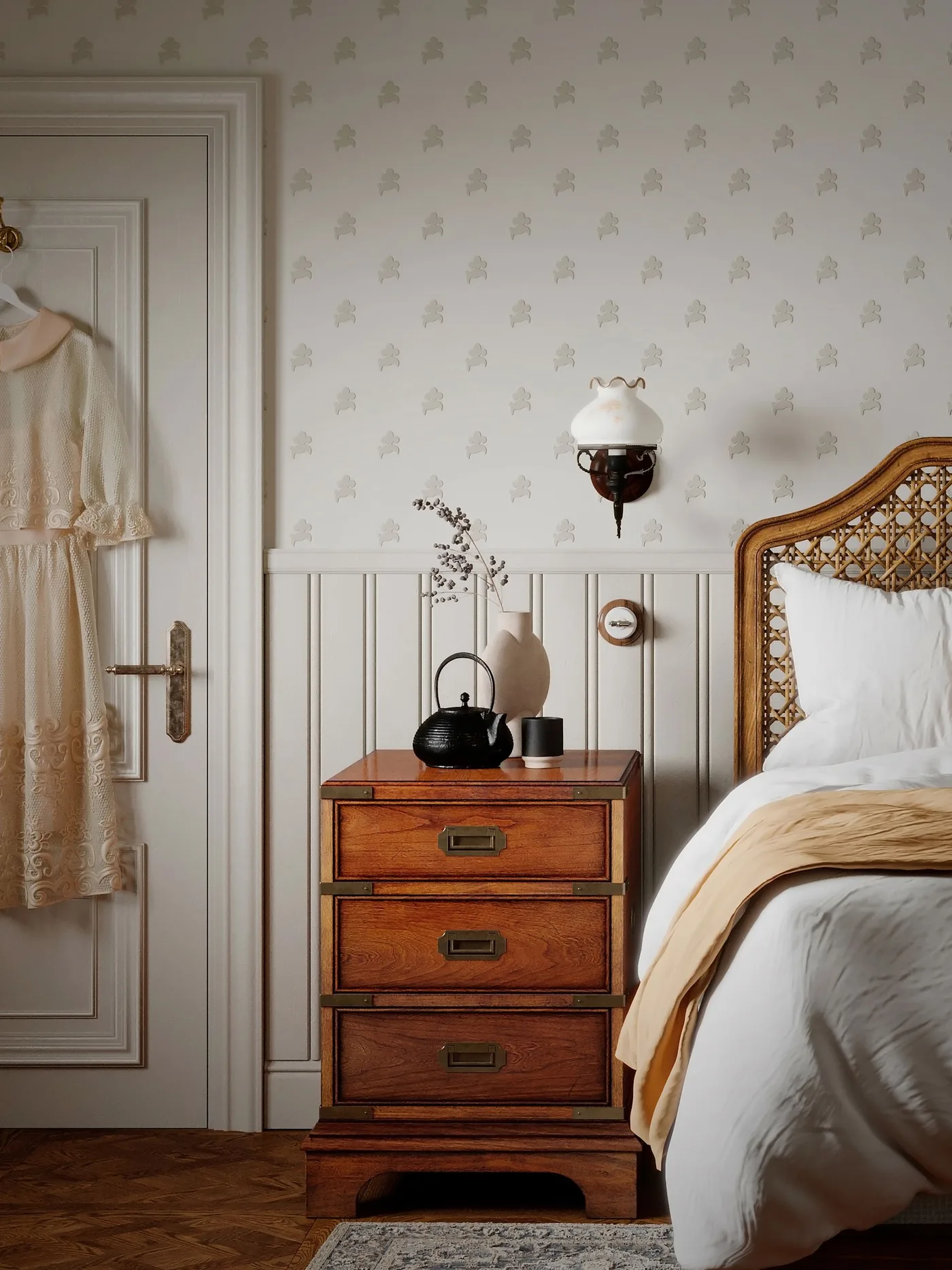 Pale flower sprigs on cream wallpaper above vertical paneling beside a cane headboard and wooden chest.