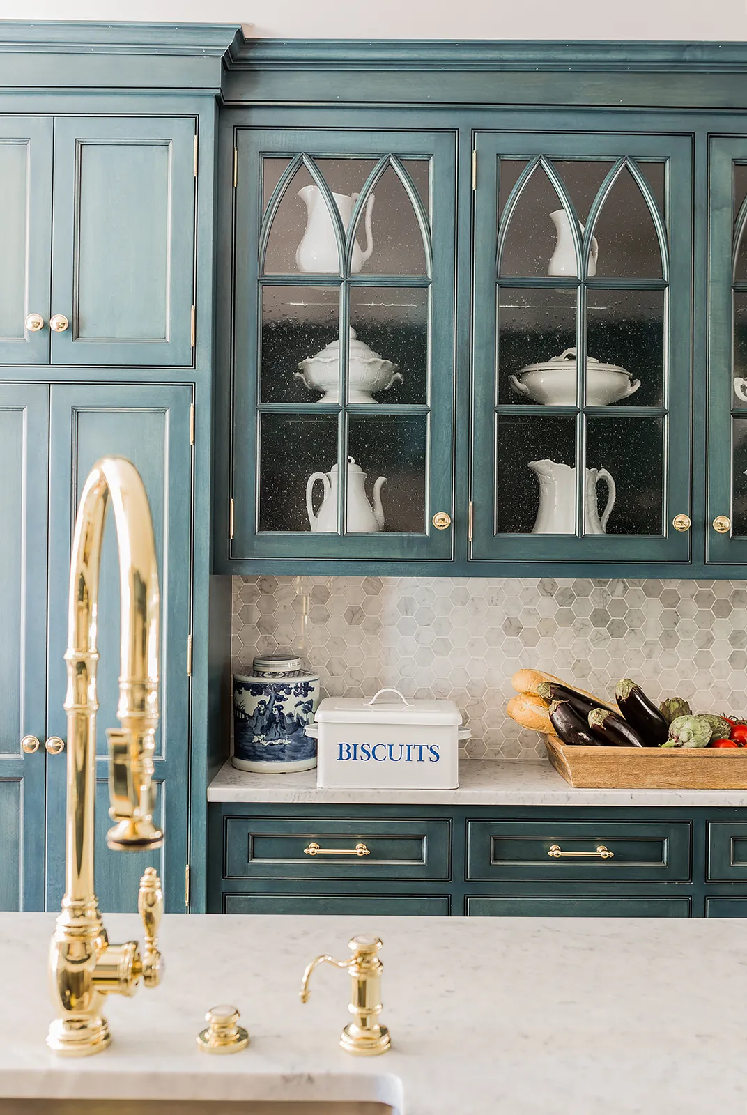 Teal cabinets include patterned glass upper doors above a pale worktop