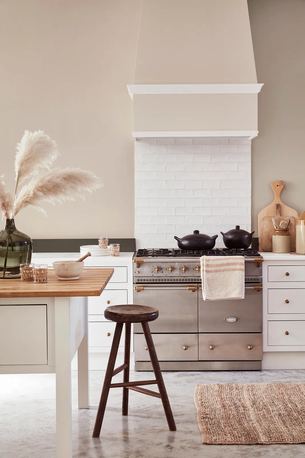 White painted kitchen cabinets with a pale hood, neutral walls and a timber tabletop