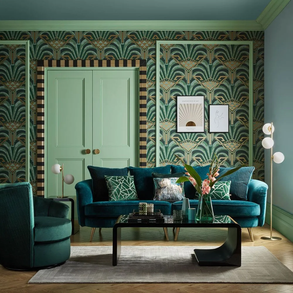 Green patterned wallpaper surrounds mint-green double doors behind a teal sofa, matching armchair and black coffee table