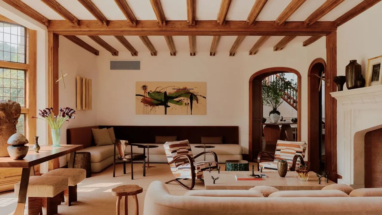 Light seating stands beneath exposed timber beams in a broad room.