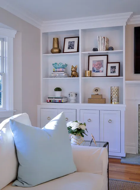 Light blue built-in shelves sit beside a pale chair and small framed pictures.