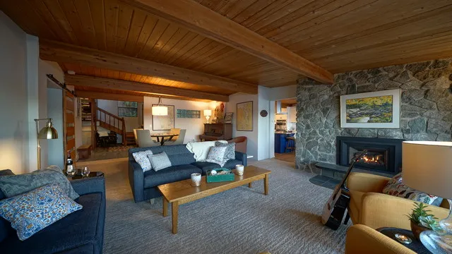 Blue seating sits beneath a broad timber ceiling beside a simple wood table.