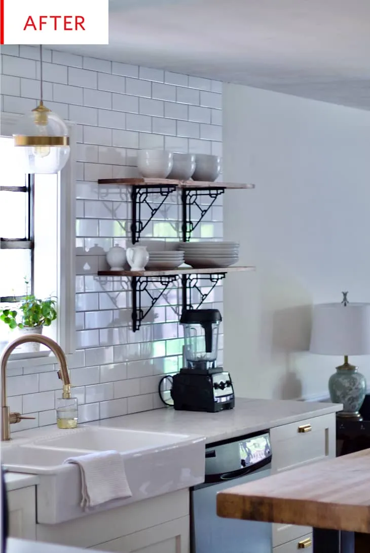 Farmhouse apron-front sink in front of subway tile, dark metal shelf brackets and wood island