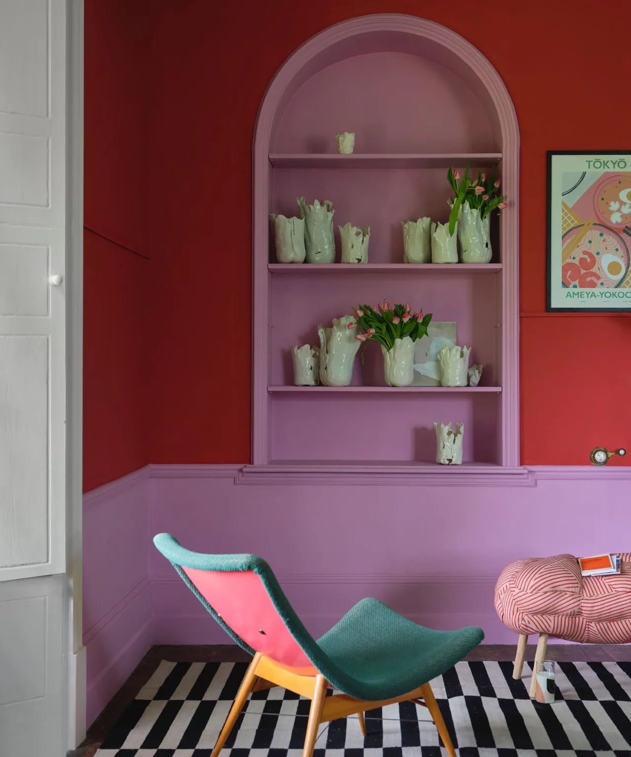 Pink arched alcove within red walls above a green chair and black-and-white checked flooring