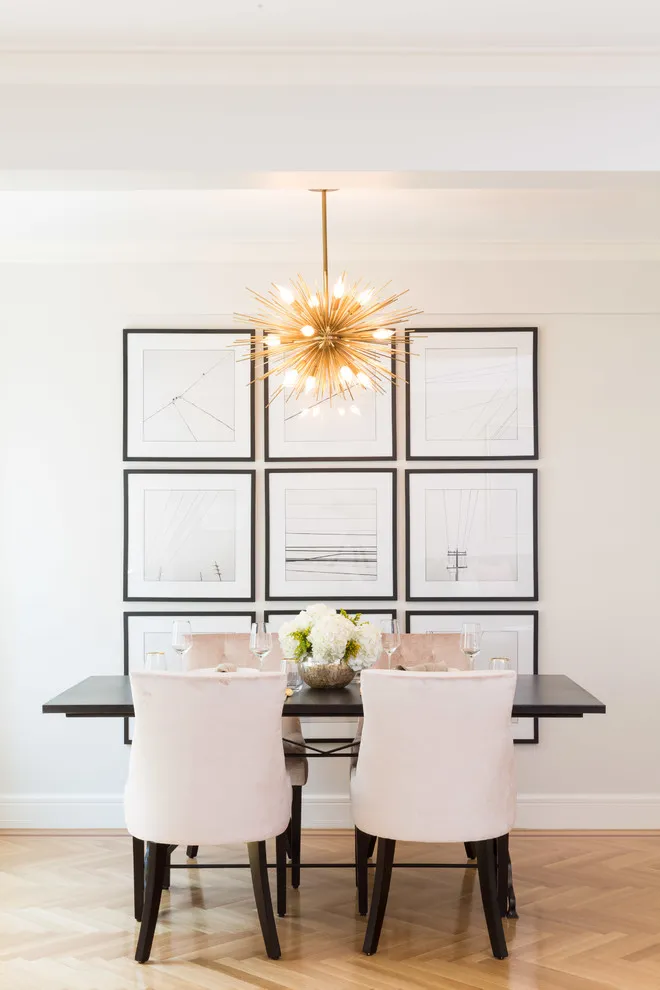 A rectangular table with four pale chairs sits beneath a small picture grid