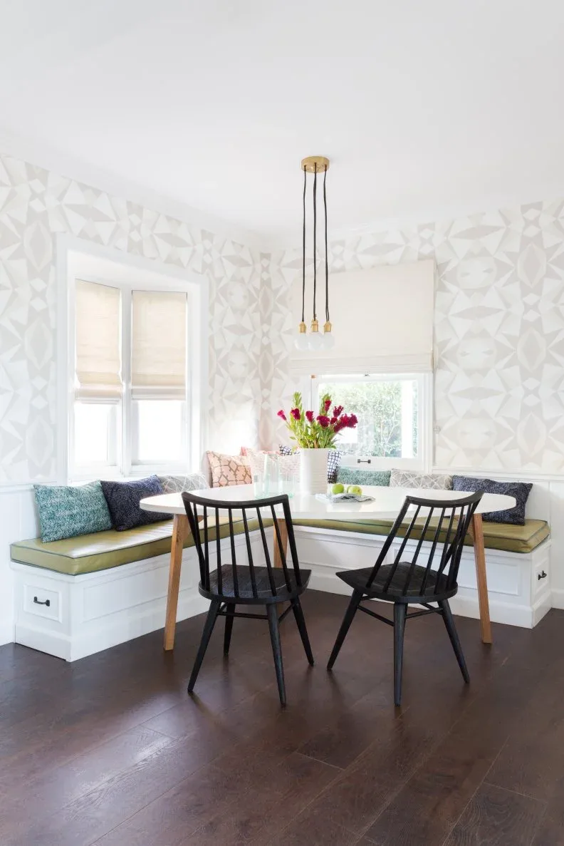White corner dining bench with end drawers and yellow-green cushions beside a pale table and black chairs