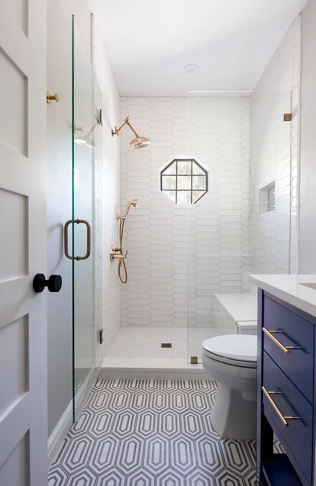 Repeated gray geometric outlines cover the floor of a narrow bathroom with a dark blue vanity