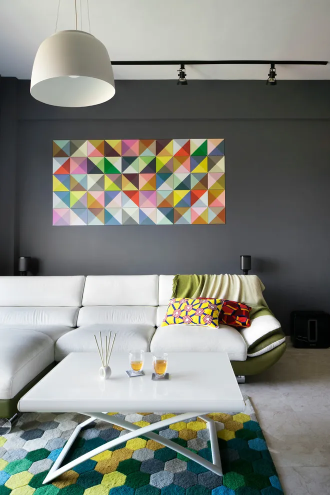 A colorful geometric artwork sits above a pale sectional against a dark wall