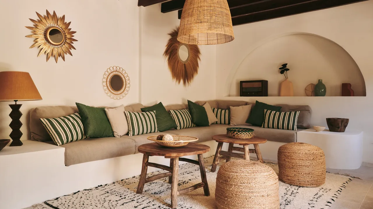 A built-in corner seat sits beneath warm woven lighting beside natural poufs.
