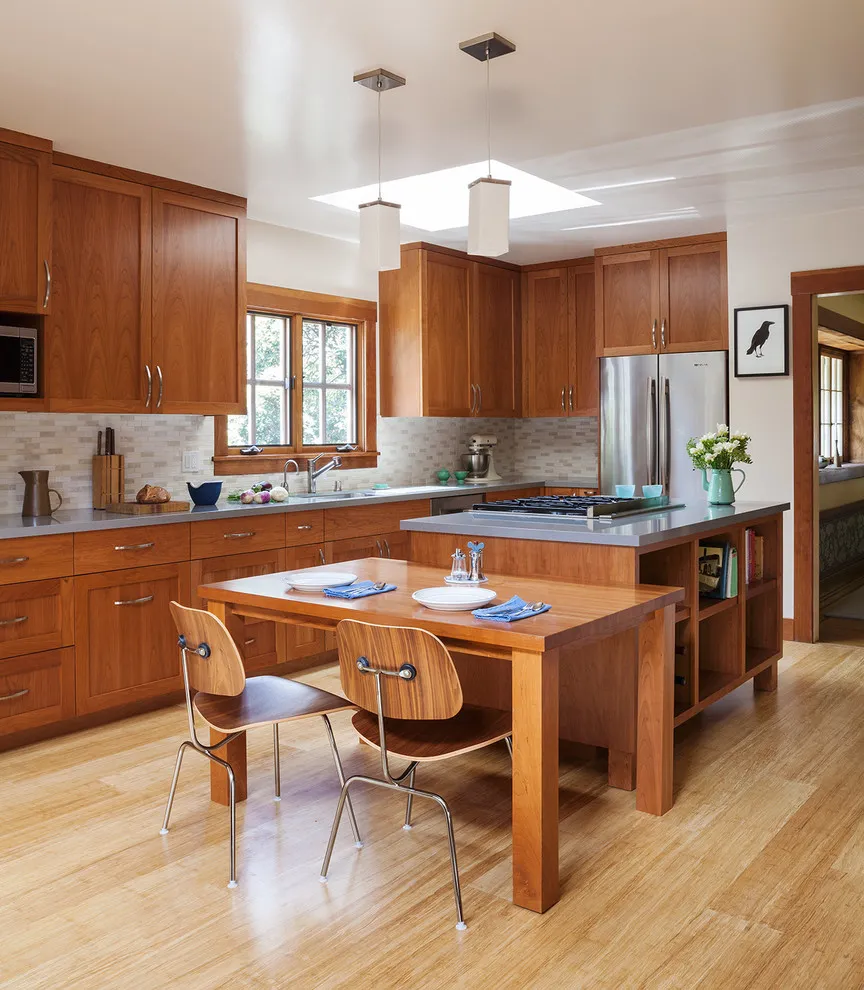 Warm wood kitchen cabinets and an island beside a timber dining table with two chairs