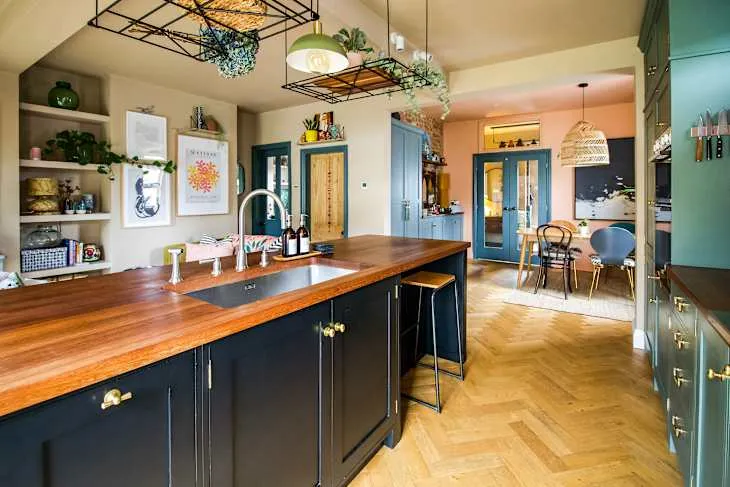 Lived-in boho kitchen and dining area with natural wood island, blue-green cupboards, open display and patterned details