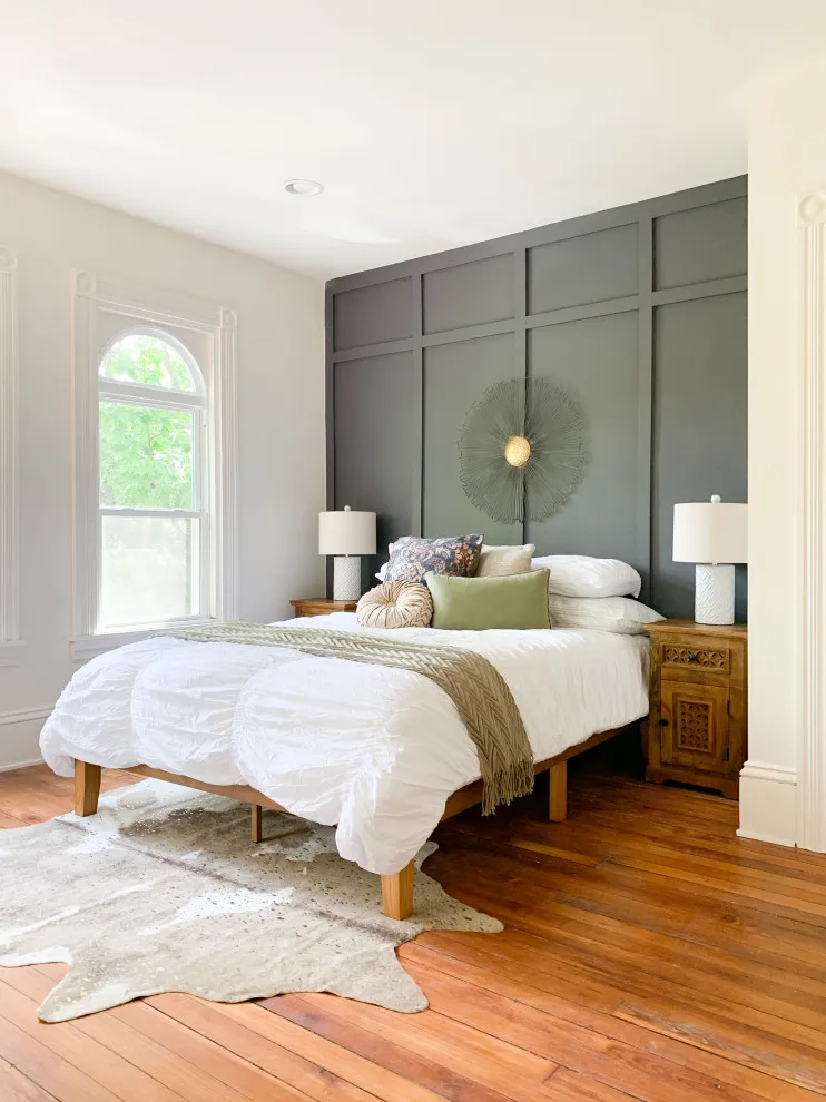 A gray paneled grid frames a bed beside an arched window