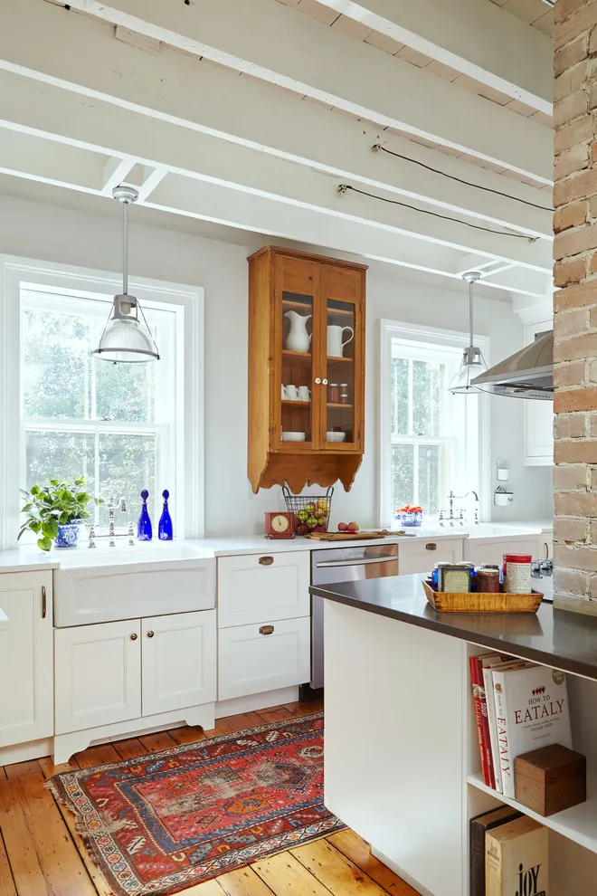 White lower cabinets sit below a timber glass-front cupboard near a window