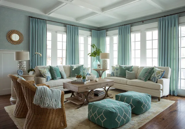 Pale blue walls frame light sofas, woven chairs and soft blue poufs.