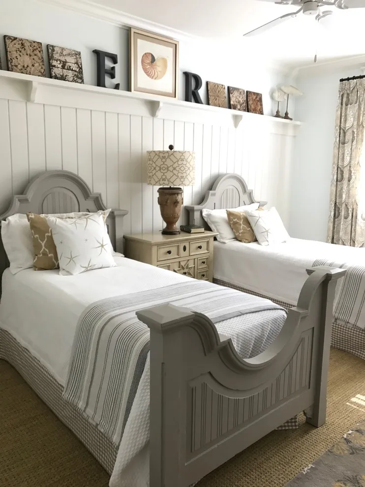 Pale vertical boards run behind two traditional beds beneath a narrow display ledge