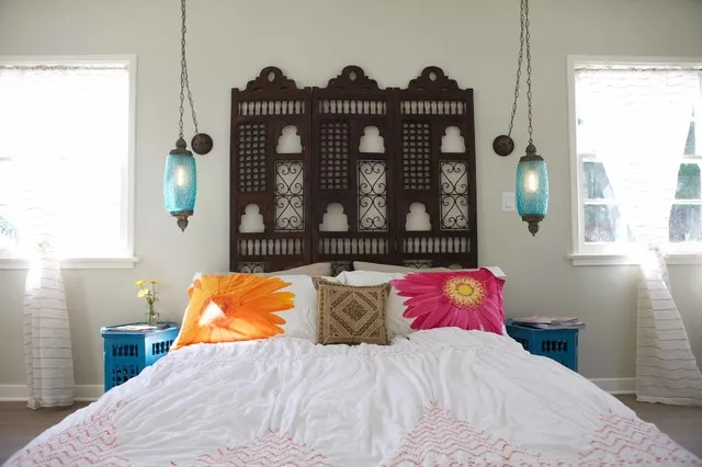 A dark carved headboard stands above pale bedding between small painted bedside tables.