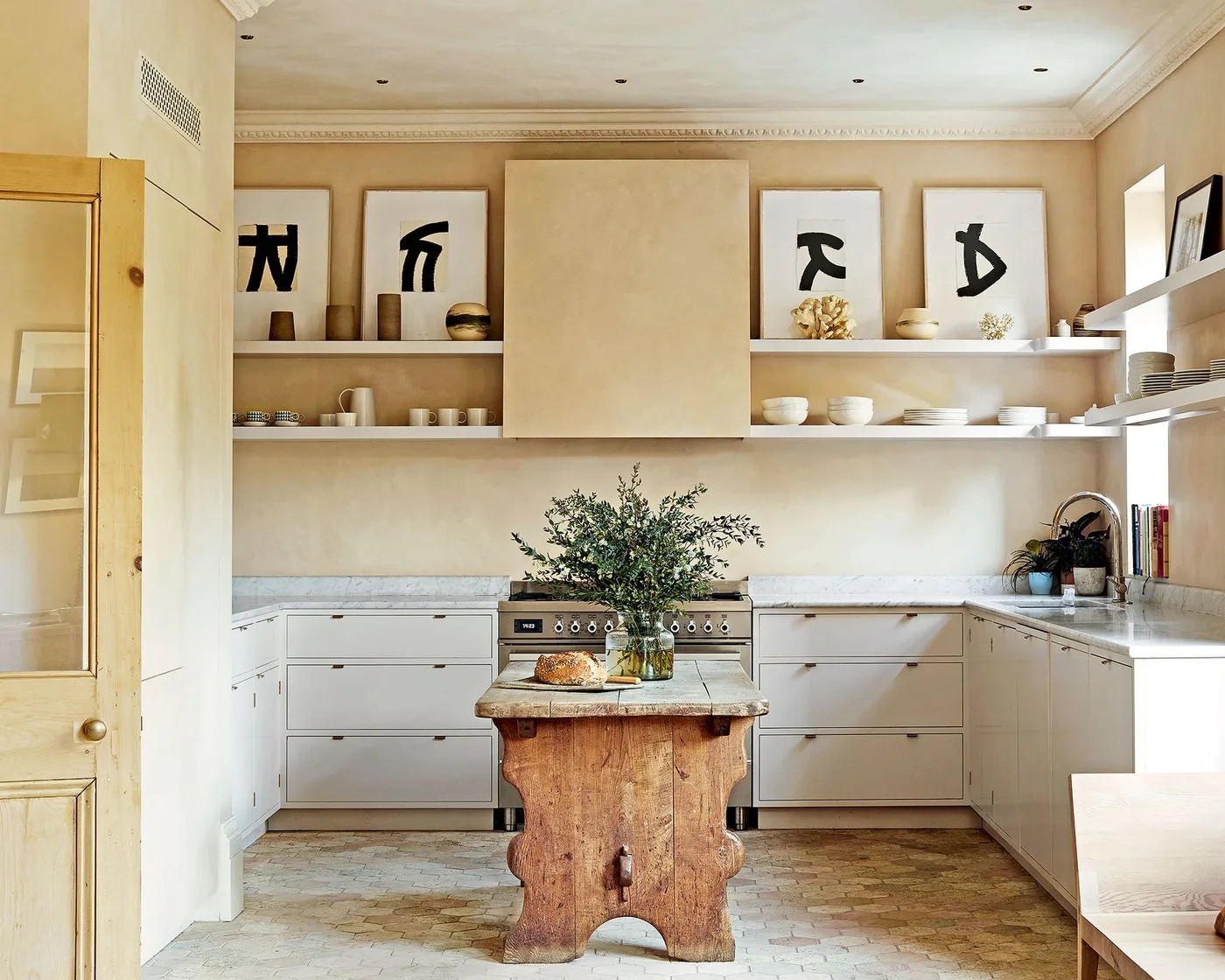 Pale kitchen with framed lower cabinets, open shelves, a range cooker and a small shaped wooden island.