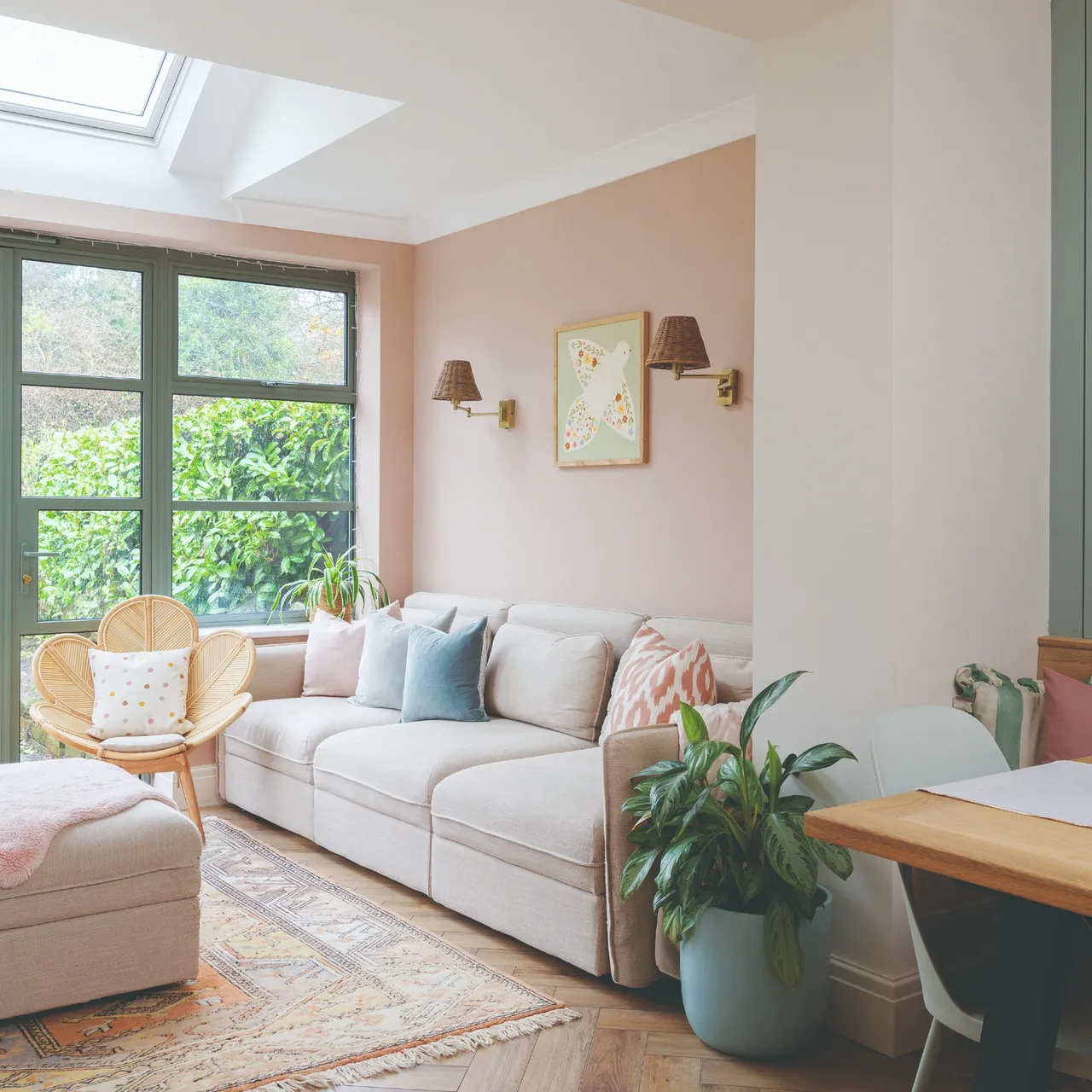 A small pale sofa sits beside a garden window beneath a skylight