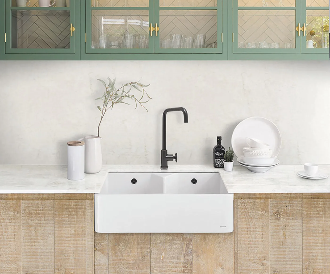 Light brown textured base cabinets below green glazed uppers, a white apron-front sink and black faucet.
