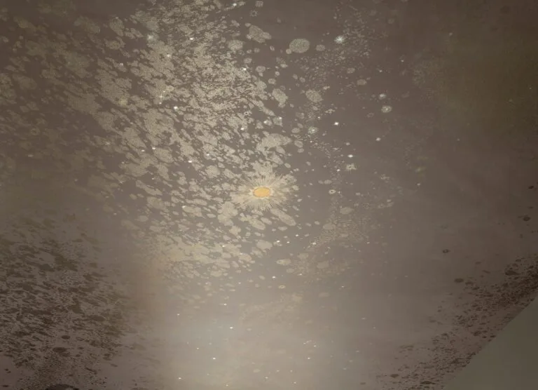 Close view of a pale celestial ceiling pattern with scattered light speckles and a small circular ceiling light.