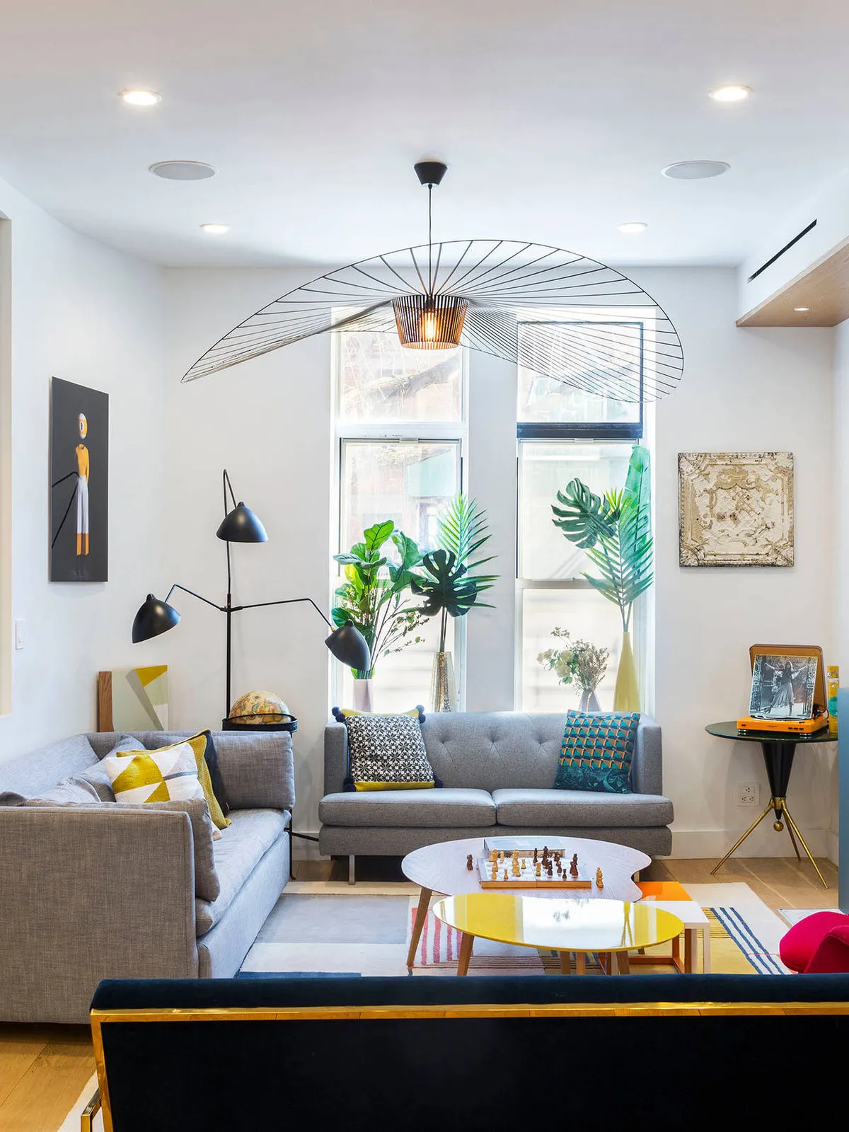 A sculptural pendant hangs above pale seating, a blue sofa and a bright coffee table.