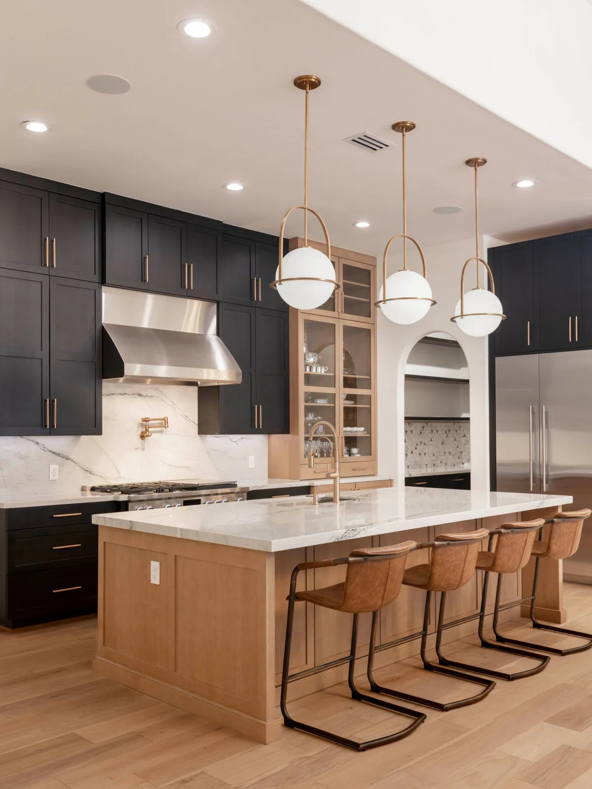 Black wall cabinets surround a timber island and pale counters.