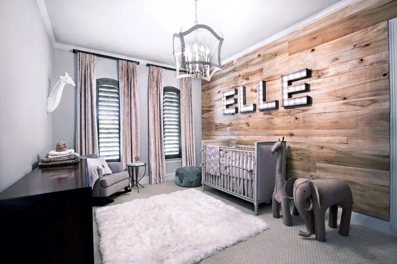Nursery with broad wooden wall, quieter crib, tall patterned curtains, pale rug, adult seating and animal-shaped decorations.