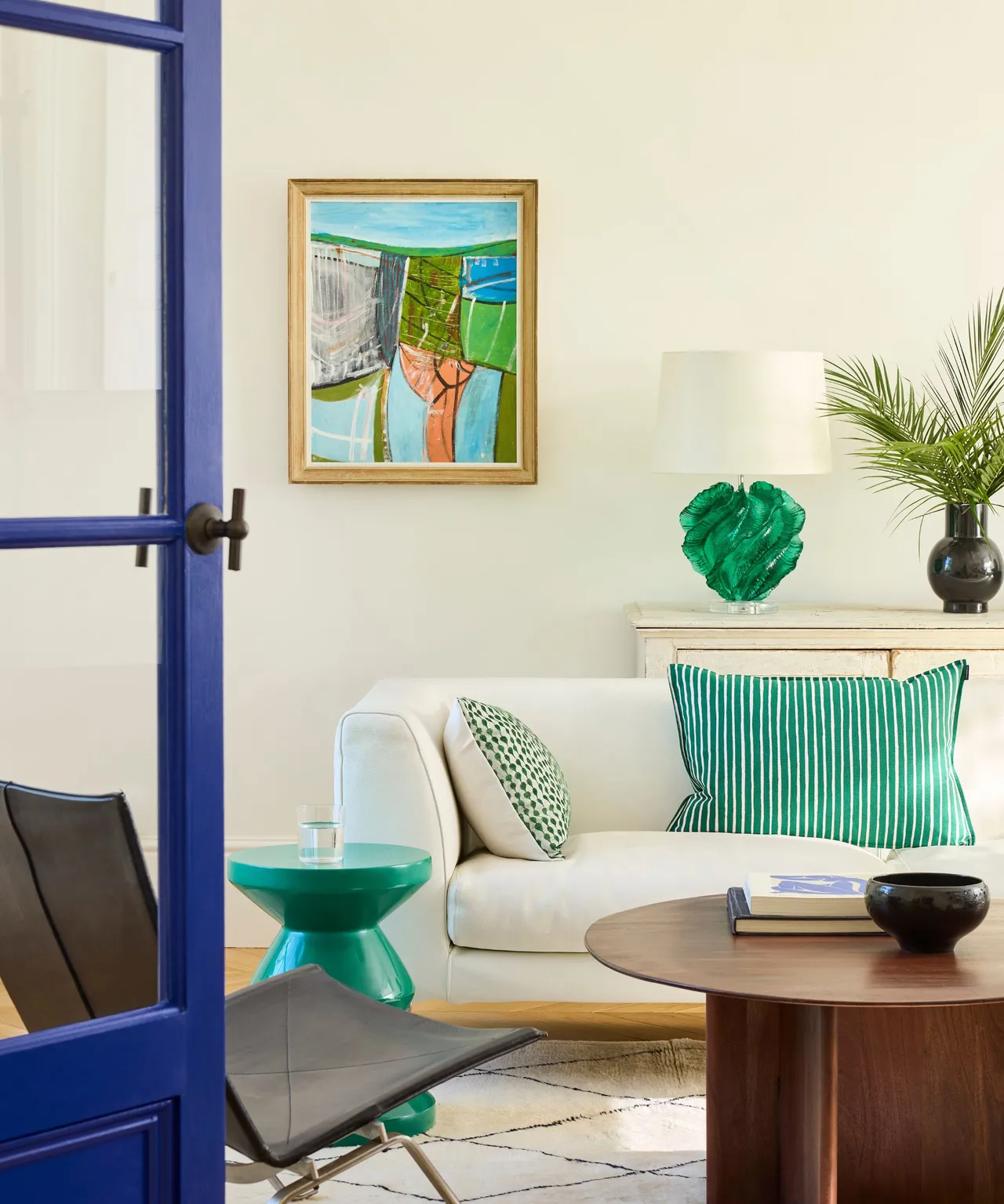 A cream sofa sits beside green cushions and a small green side table