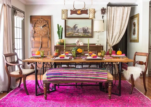 A striped upholstered bench sits on a vivid pink rug beside a timber table and assorted chairs.