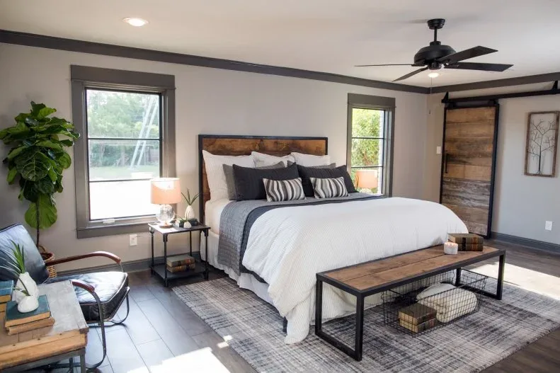 Pale bedroom with a wood headboard, wood-topped bench, sliding wood door and dark furniture frames