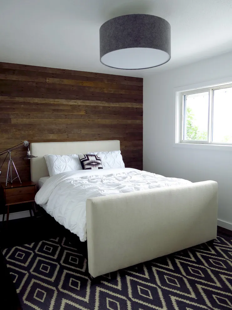 Horizontal timber boards cover the wall behind a light upholstered bed