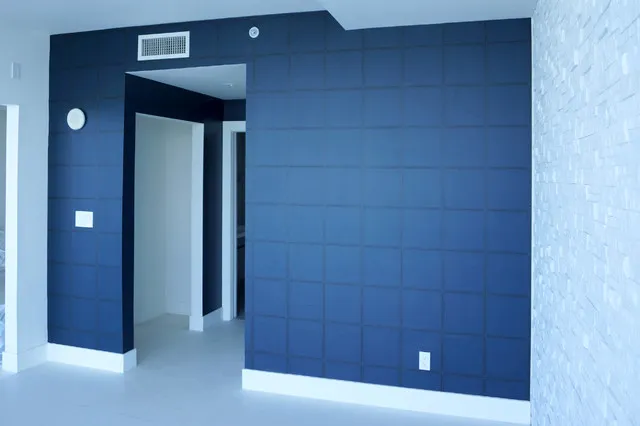 Deep blue wallpaper covers a wall beside an open doorway and pale trim.
